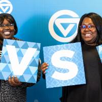 Mentors taking photos at the photobooth with GVSU sign